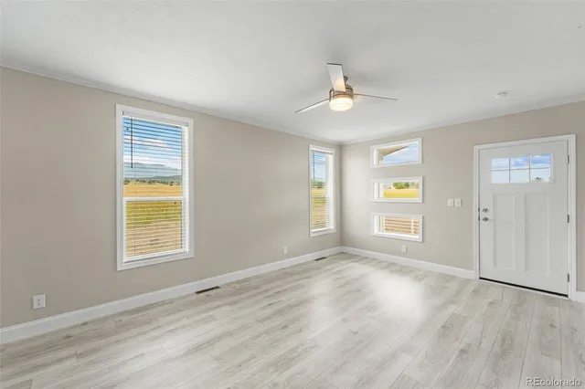 a view of an empty room with a window and wooden floor