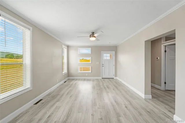 a view of an empty room with window and wooden floor