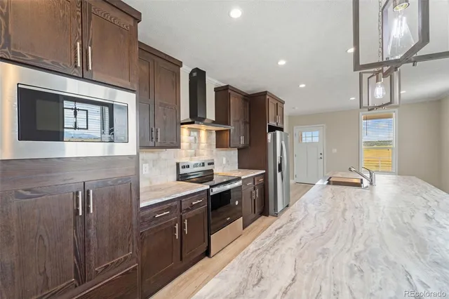 a large kitchen with stainless steel appliances granite countertop a lot of counter space and wooden floors