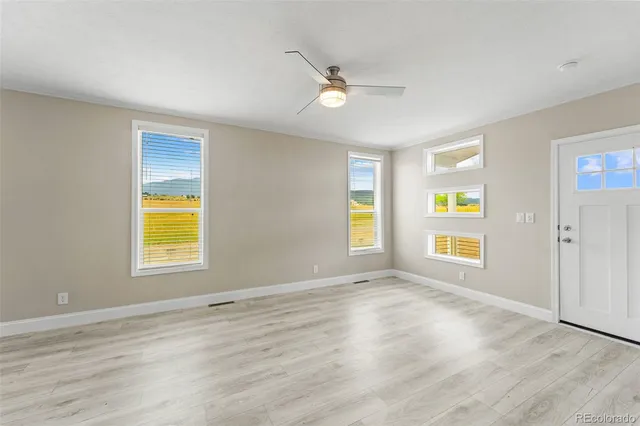 a view of an empty room with a window and wooden floor