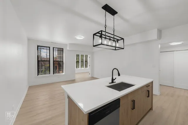 a kitchen with stainless steel appliances granite countertop a sink a microwave oven a refrigerator white cabinets and wooden floor