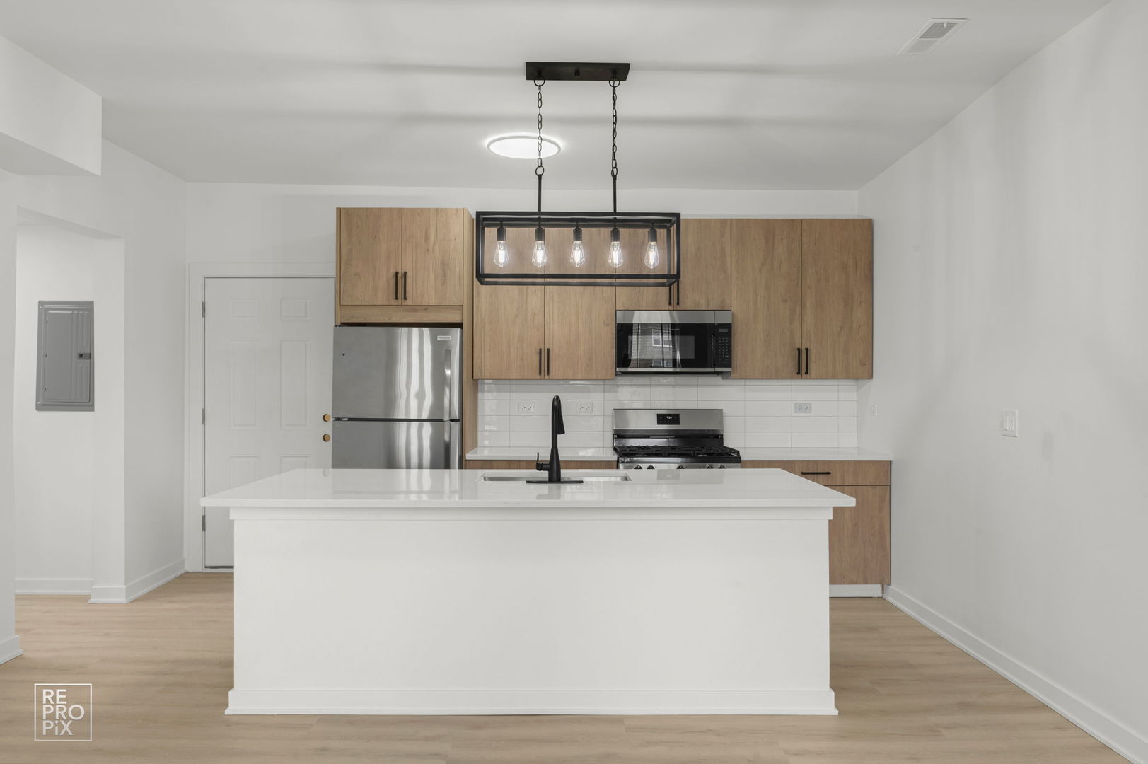 7717 North Sheridan Road, Unit 2F Chicago, IL 60626 - Photo 4 of 11 a kitchen with stainless steel appliances granite countertop a sink a microwave oven a refrigerator white cabinets and wooden floor