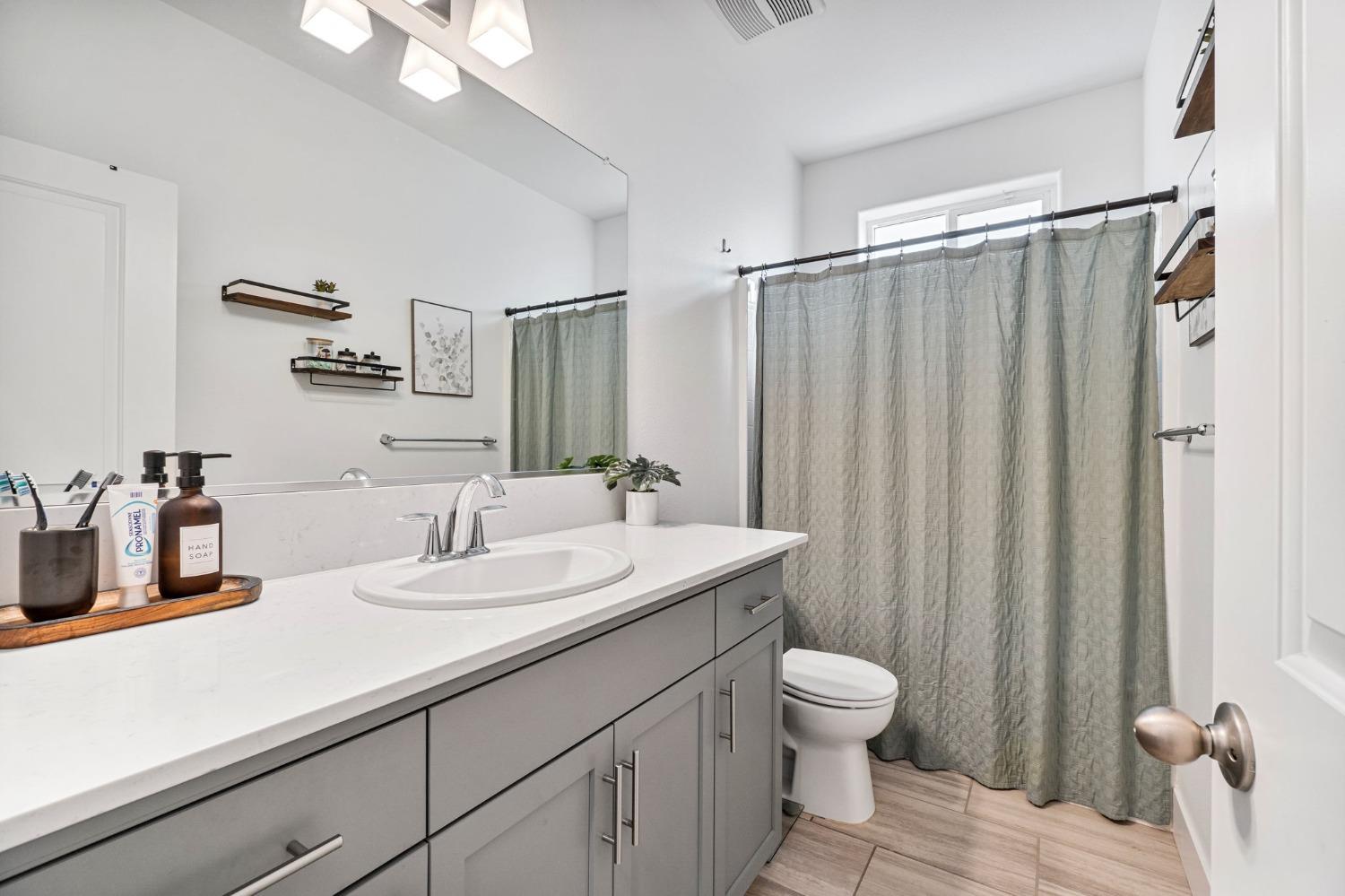 4218 Oak Knoll Road Madera, CA 93636 - Photo 15 of 37 a bathroom with a sink a toilet and a large mirror