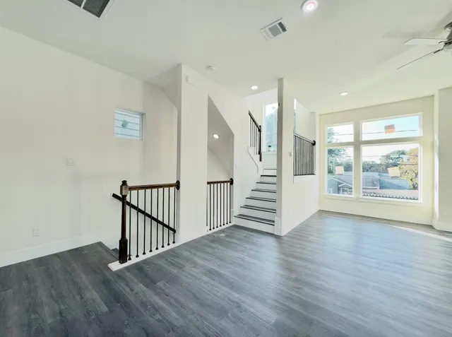 a large white kitchen with stainless steel appliances kitchen island a stove a refrigerator a sink dishwasher and a stove with wooden floor