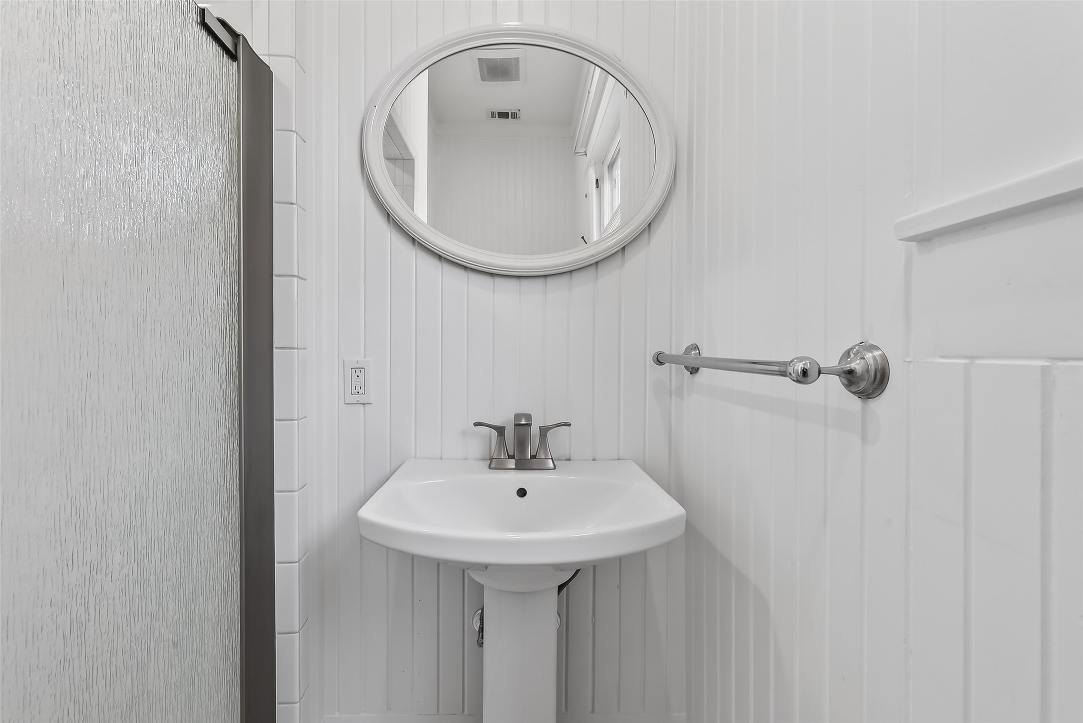 38011 Spur 149 Road Magnolia, TX 77354 - Photo 31 of 50 This charming full bathroom features a sleek pedestal sink, elegant white wainscoting, and a stylish round mirror, offering a bright and inviting retreat.