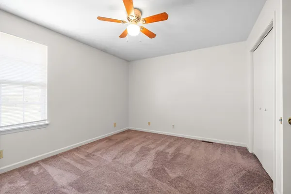 an empty room with a window and a fan