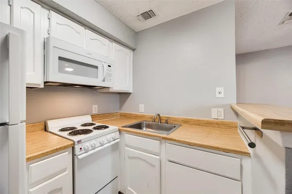 a view of a kitchen with wooden floor a ceiling fan and kitchen space