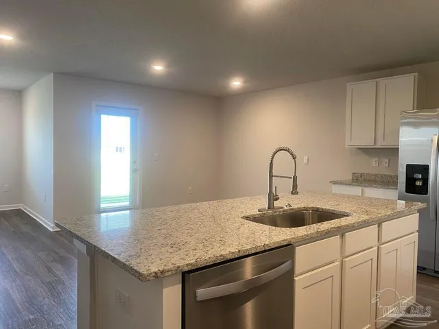 a kitchen with granite countertop a sink and white cabinets