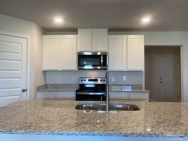a kitchen with kitchen island granite countertop a stove and a sink with granite countertops