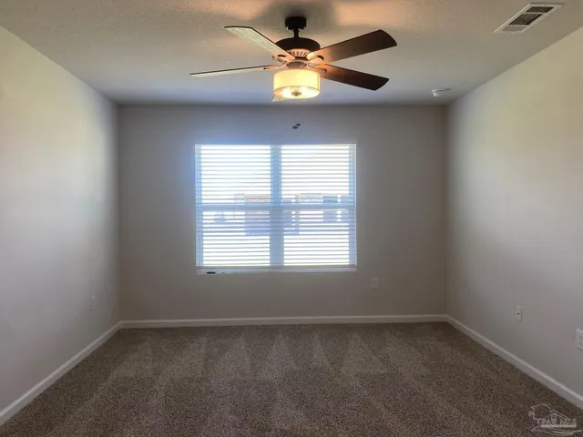 an empty room with a window and a fan