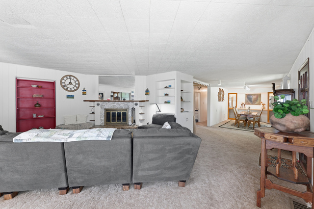 365 North Main Street Fillmore, UT 84631 - Photo 42 of 51 Spacious interior featuring a decorative fireplace with a stone surround, built-in shelving, white walls, and neutral carpeting