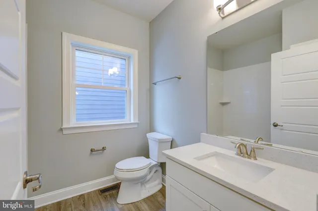 a bathroom with a granite countertop toilet a sink and a mirror