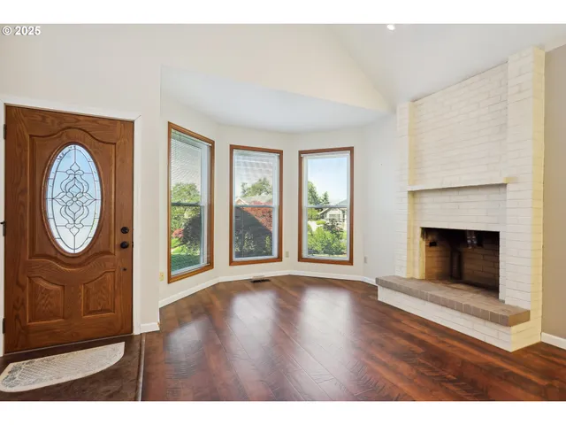 a view of a livingroom with furniture wooden floor a fireplace and a large window