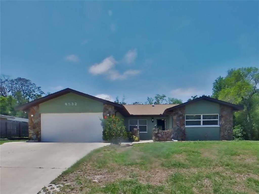 6532 Pinehurst Drive Spring Hill, FL 34606 - Photo 1 of 1 a front view of a house with a garden and plants