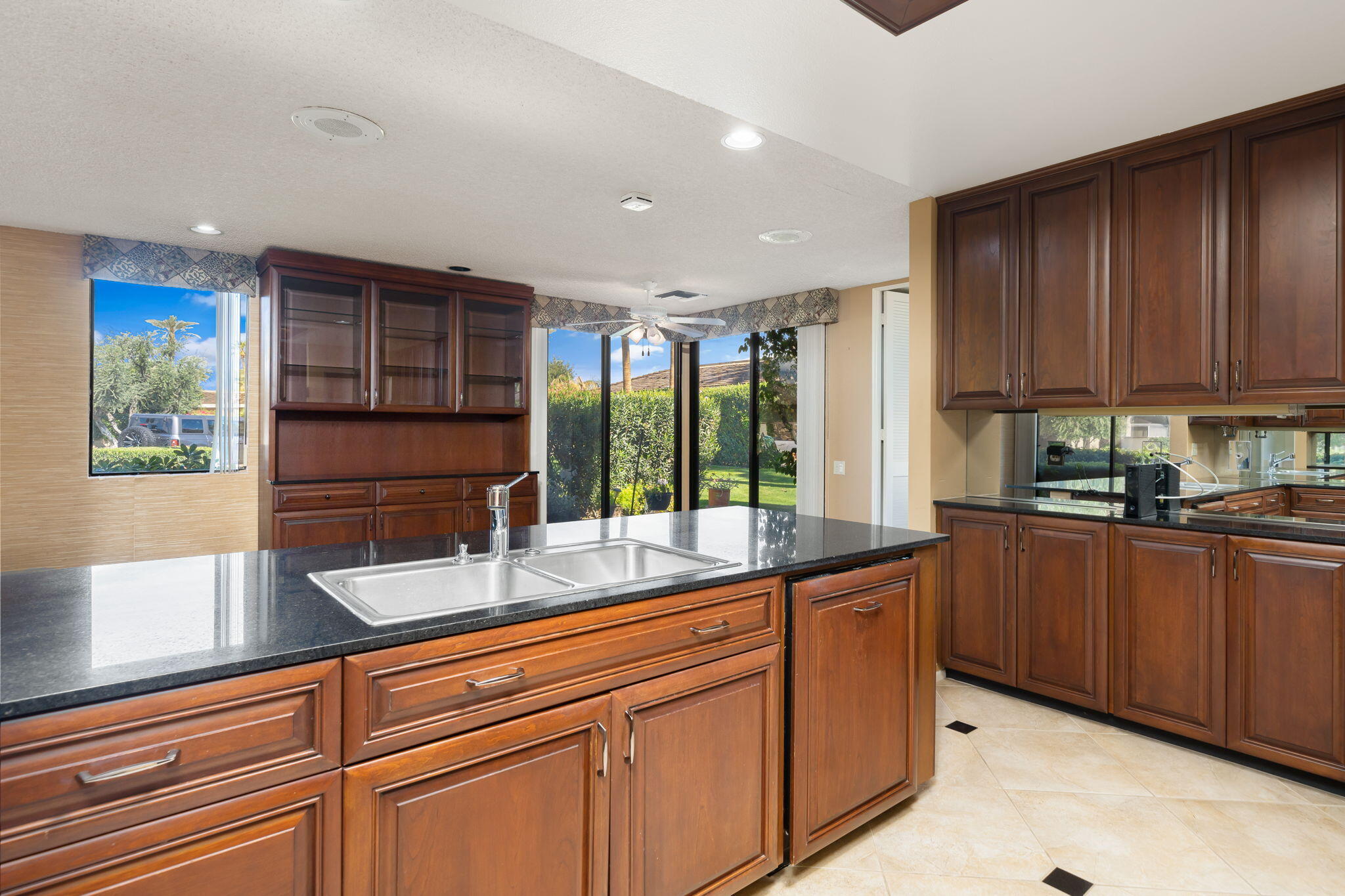 140 Columbia Drive Rancho Mirage, CA 92270 - Photo 9 of 31 a kitchen with stainless steel appliances granite countertop wooden cabinets a stove a sink and a large window