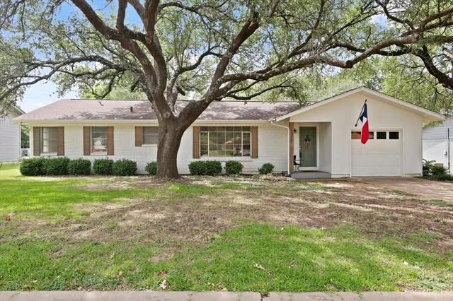 a view of a yard in front of a house with large trees