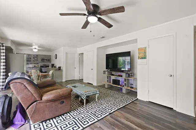 a living room with furniture a flat screen tv and kitchen view