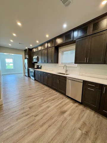 a large kitchen with stainless steel appliances kitchen island granite countertop a sink and cabinets