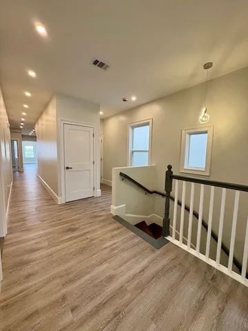 a view of a hallway with wooden floor and windows