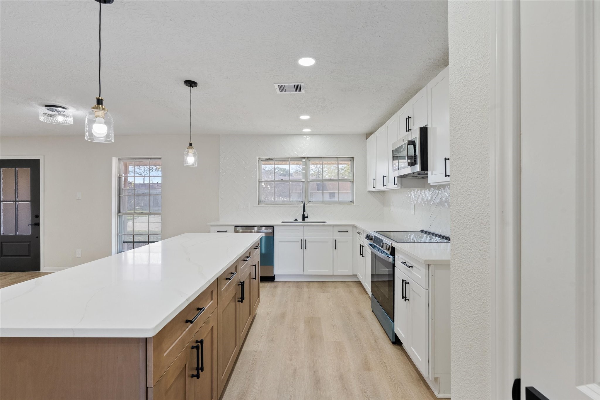 10403 Winding Trail Road La Porte, TX 77571 - Photo 9 of 26 a large kitchen with kitchen island a sink dishwasher a stove a dining table and chairs with wooden floor