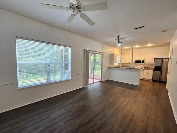 a view of a kitchen with a sink a kitchen island wooden floor and a window