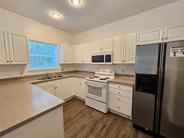 a kitchen with granite countertop white cabinets and stainless steel appliances