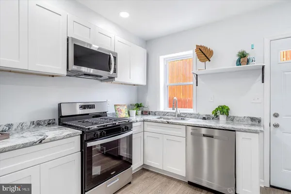 a kitchen with granite countertop white cabinets stainless steel appliances and a window