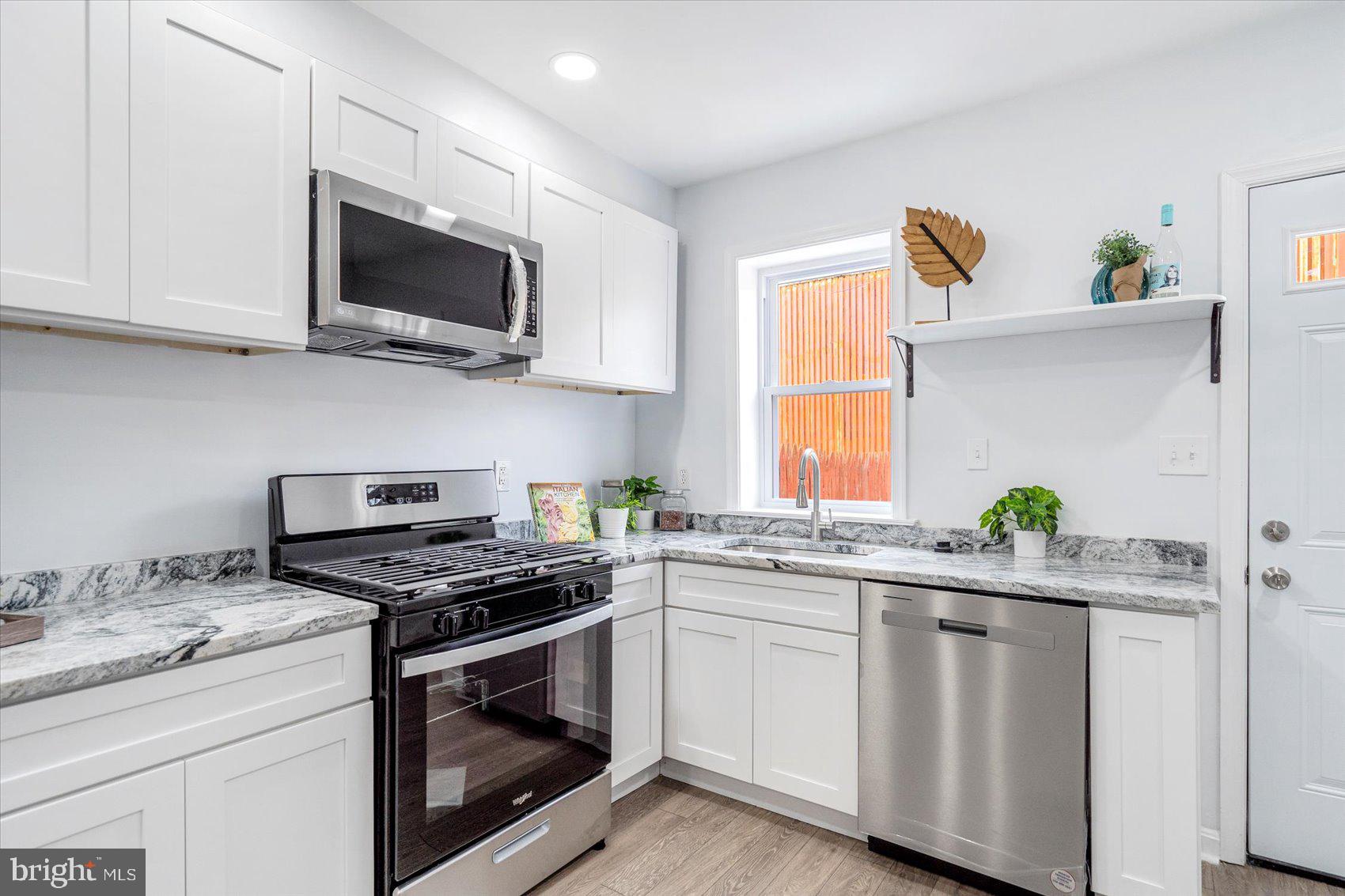 1432 Carroll Street Baltimore, MD 21230 - Photo 10 of 29 a kitchen with granite countertop white cabinets stainless steel appliances and a window