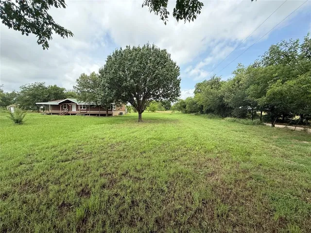 a view of yard with green space and trees in the background