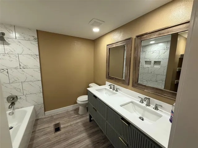 a bathroom with a double vanity sink mirror and bathtub