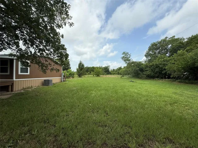 a backyard of a house with plants and large trees