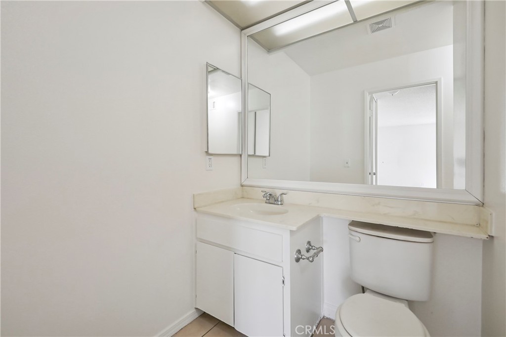 45546 Aladdin Street, Unit B101 Indio, CA 92201 - Photo 11 of 18 a bathroom with a toilet sink vanity and mirror