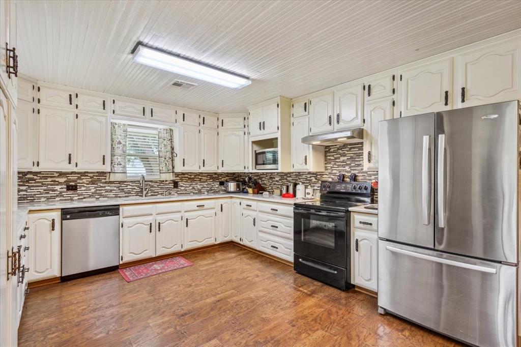 221 County Road 157 Riesel, TX 76682 - Photo 9 of 30 Kitchen with appliances with stainless steel finishes, a sink, under cabinet range hood, light countertops, and wood ceiling