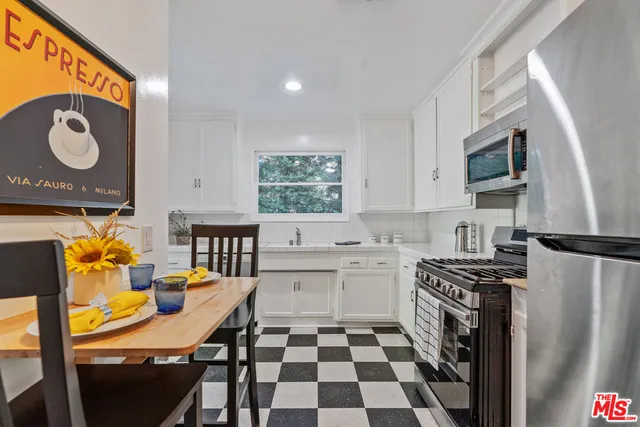 a kitchen with stainless steel appliances granite countertop a sink a stove a chimney a dining table and chairs