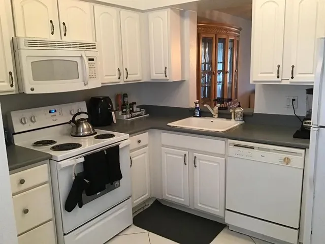 a kitchen with granite countertop white cabinets and white appliances
