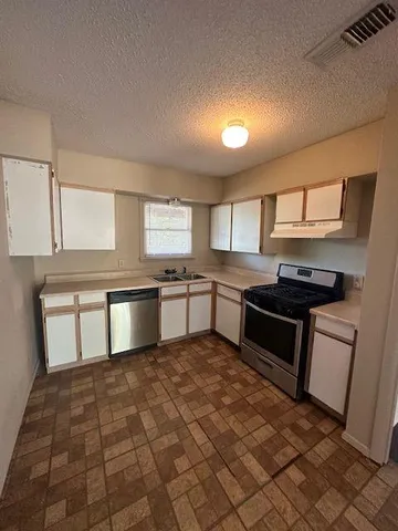 a kitchen with granite countertop a stove a sink and a refrigerator