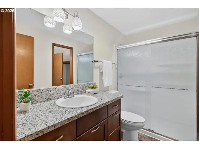 a bathroom with a granite countertop sink toilet and shower