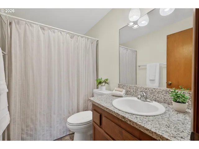 a bathroom with a granite countertop sink toilet and a mirror