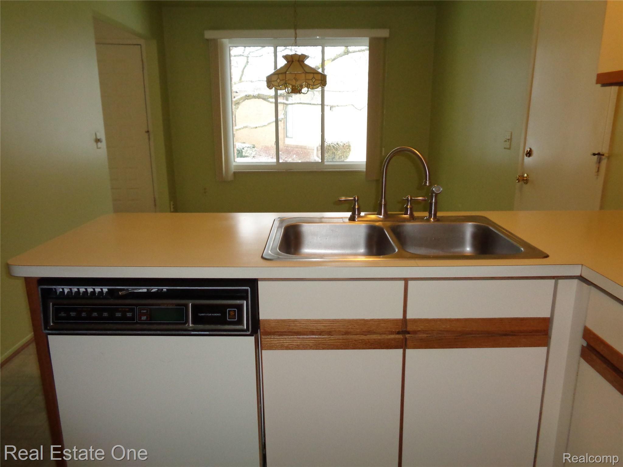 624 Tennyson, Unit 113 Rochester, MI 48307 - Photo 8 of 51 View 2 with dishwasher, stainless sink and newer faucet. Access door to garage is on right.