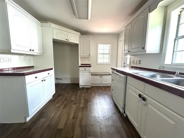 a kitchen with a sink a window appliances and cabinets