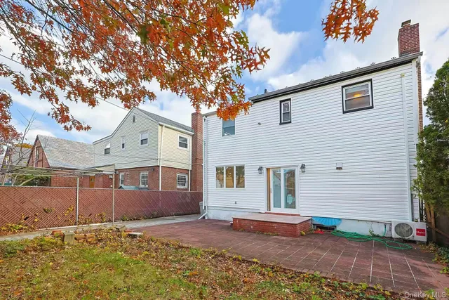 a view of a white house with a large tree