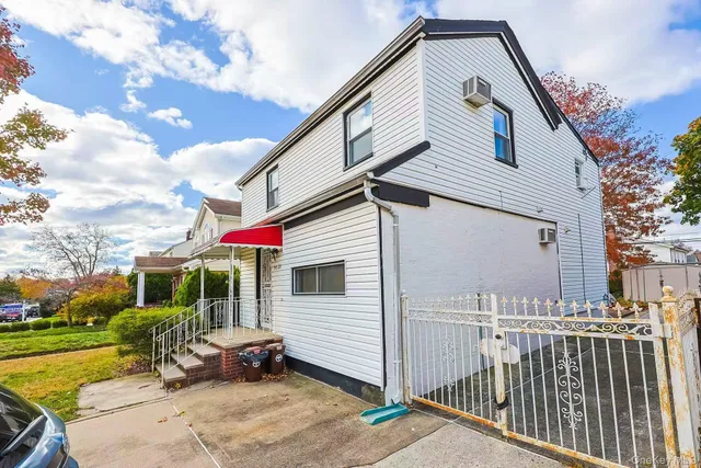 a view of a white house with a small yard and a large tree