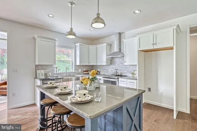 a kitchen with stainless steel appliances granite countertop a dining table chairs and white cabinets