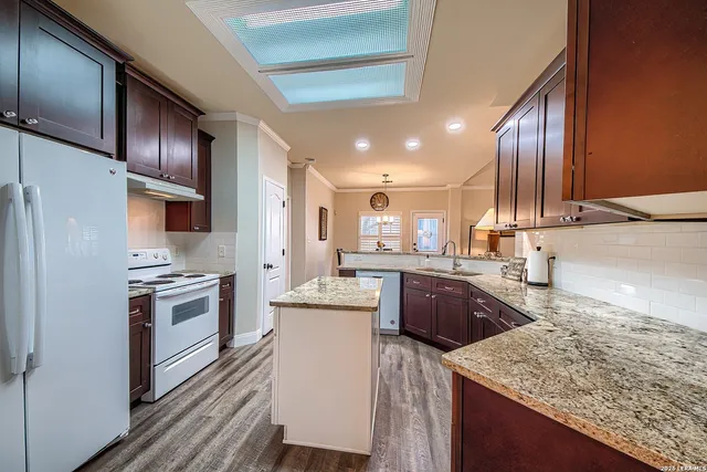 a kitchen with kitchen island granite countertop wooden cabinets and a refrigerator