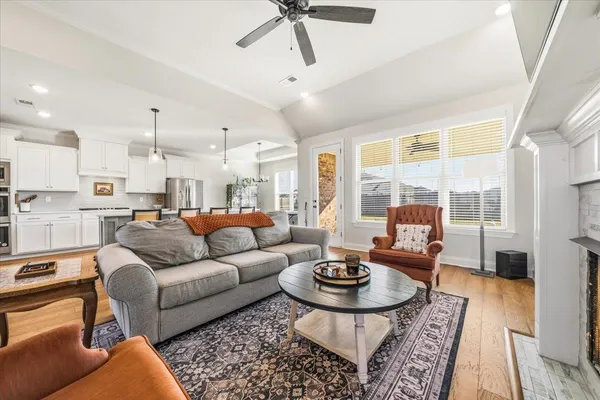 a living room with furniture kitchen view and a large window