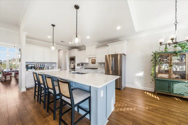 a kitchen with stainless steel appliances kitchen island granite countertop a table chairs and a wooden floor
