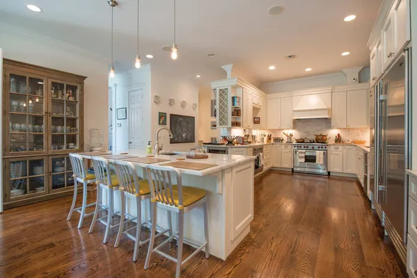 a kitchen with stainless steel appliances kitchen island granite countertop a stove a refrigerator a oven a sink with island and chairs with wooden floor