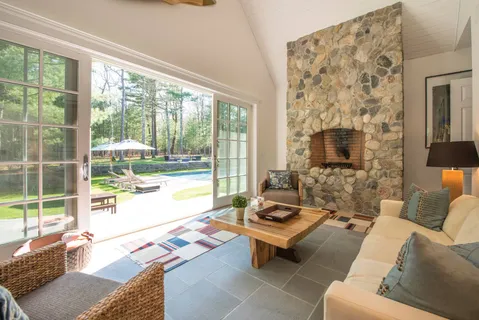 a living room with furniture and a floor to ceiling window next to a yard