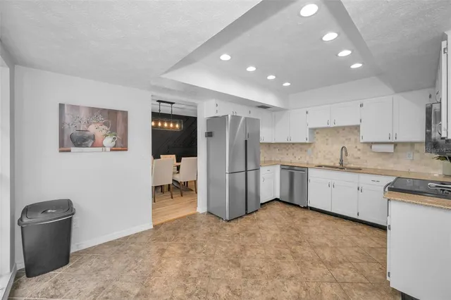 a kitchen with a refrigerator a stove a sink and white cabinets with wooden floor