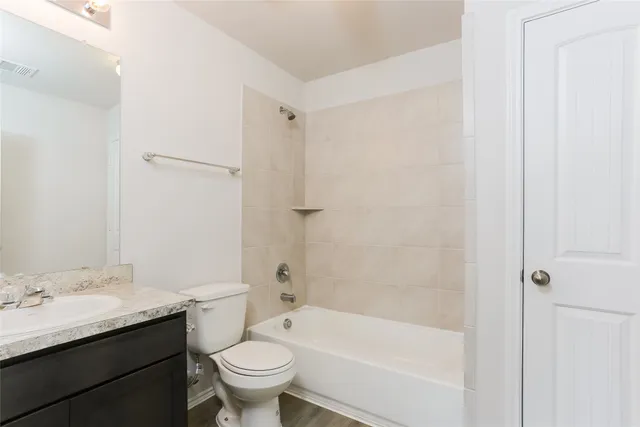 a bathroom with a granite countertop toilet a sink and a bathtub